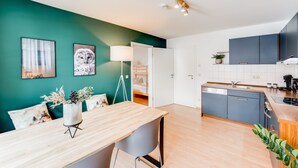A modern kitchen with grey cabinets, a wooden countertop, and a dining area with a table and chairs. - VYLD: Owl's nest (Bad Hindelang)