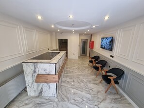 A modern kitchen with marble countertops, a wooden bar counter, and black chairs. - ELİTE PARK HOTEL & SUİTES (Istanbul)