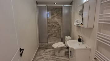 Un baño moderno con suelo de mármol, inodoro, lavabo y ducha.