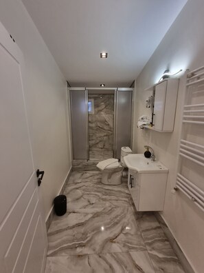 A modern bathroom with a marble floor, a toilet, a sink, and a shower. - ELİTE PARK HOTEL & SUİTES (Istanbul)