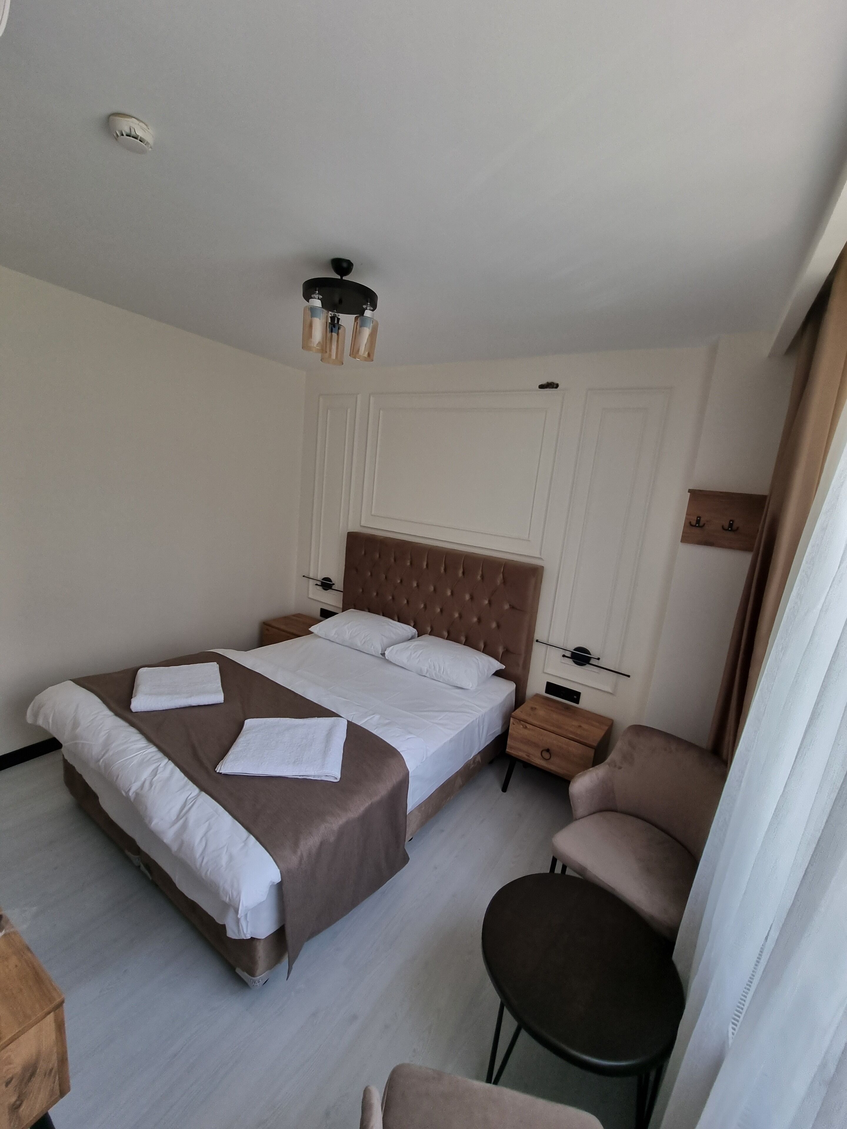 Un dormitorio ordenado con una cama grande, mesitas de noche, una silla y una pequeña mesa.