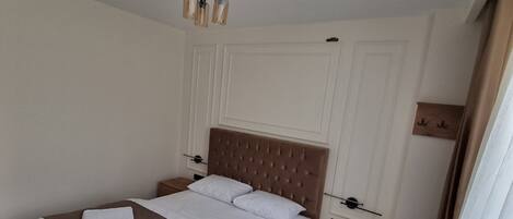 Un dormitorio ordenado con una cama grande, mesitas de noche, una silla y una pequeña mesa.