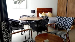 Een kamer met een bed, een ronde tafel en vier stoelen.