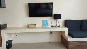 Een moderne woonkamer met een flatscreen televisie aan de muur, een bijzettafeltje met een lamp en een bank.
