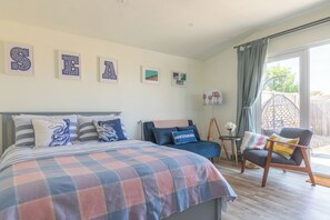 A bedroom with a bed, a chair, a small table, and a window with curtains. - Pear Tree Cabin provides a wonderful base for exploring Whitstable and the surrounding area, celebrating special occasions, or visiting friends and family. Enjoy the local cusine and stroll back to your comfy cabin to watch the sunset. (Whitstable)