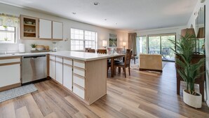 A modern kitchen with a central island, wooden flooring, and a dining area with a view of the outdoors. - Branson Condo Near 76 Strip & Silver Dollar City (Branson)