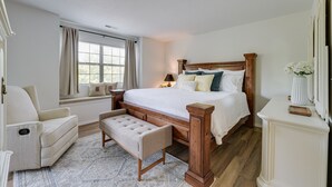 A bedroom with a large bed, a bench, a chair, and a bedside table. - Branson Condo Near 76 Strip & Silver Dollar City (Branson)