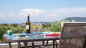 A table with a bottle of wine, two glasses, a candle, and a plate of cherries. - Modern and cozy bungalow, close to traditional villages and airport (Rhodes)