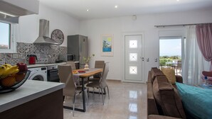 A modern kitchen with a dining area, a washing machine, and a sofa in a bright living space. - Modern and cozy bungalow, close to traditional villages and airport (Rhodes)