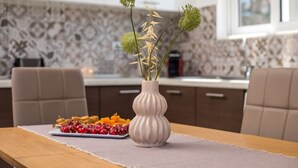A dining table with a vase of flowers and a plate of fruit. - Modern and cozy bungalow, close to traditional villages and airport (Rhodes)