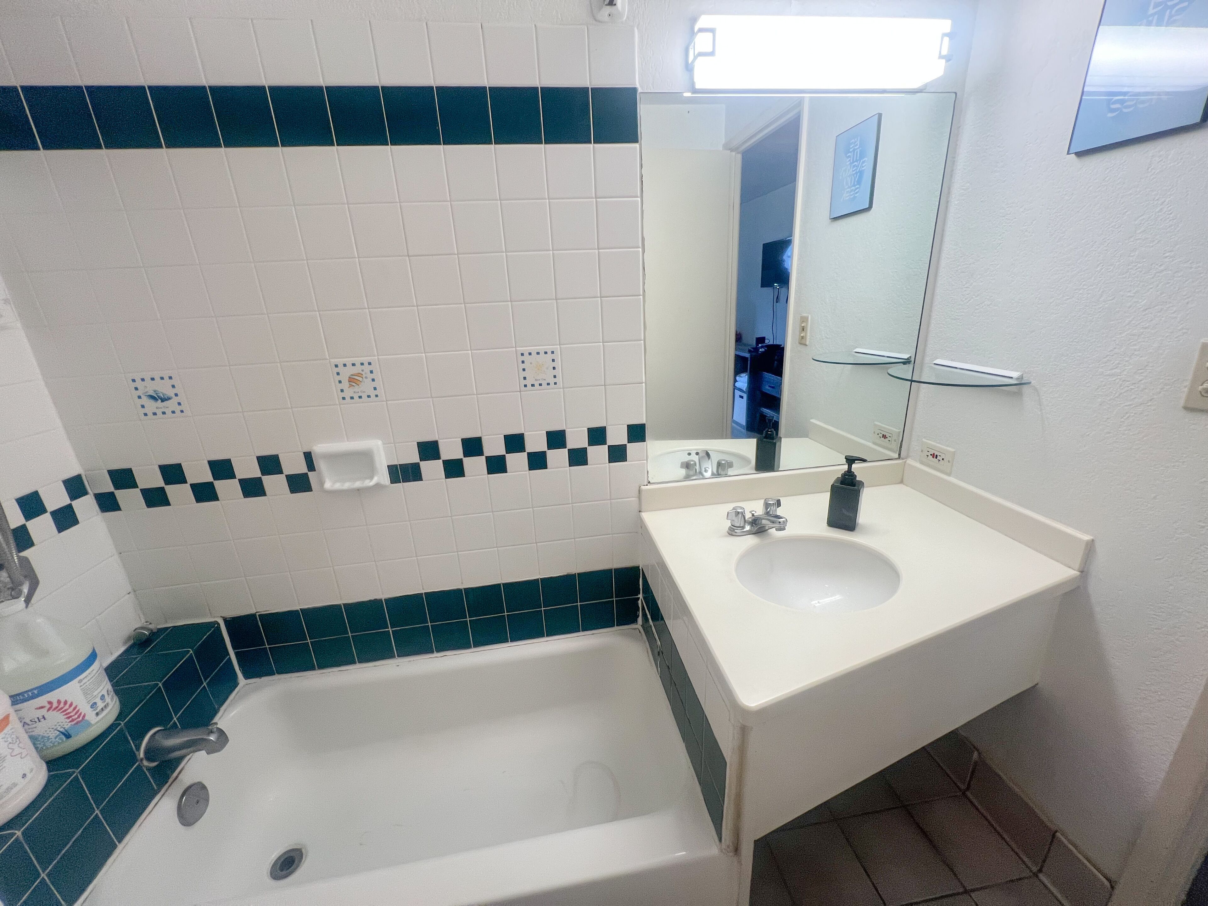 A bathroom with a bathtub, a sink, and a mirror.