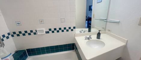 A bathroom with a bathtub, a sink, and a mirror.
