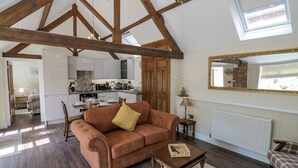 Un salon spacieux avec un canapé marron, une table basse en bois et une vue sur la cuisine et la salle à manger.