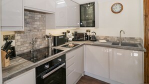 Une cuisine moderne avec des armoires blanches, un mur de fond en briques et un puits de lumière.