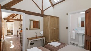 Une chambre avec deux lits, une armoire en bois, une table de chevet avec un miroir, et une salle de bain avec un lavabo et un miroir.