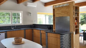 Une cuisine moderne avec des meubles en bois, un plan de travail en granit, un four encastré et une fenêtre donnant sur un paysage verdoyant.