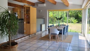 Une cuisine moderne avec des meubles en bois, un coin repas comprenant une table et des chaises, et une grande plante en pot.