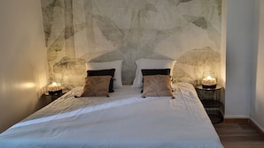 Une chambre avec un grand lit, deux tables de chevet avec des lampes et un mur à motifs derrière le lit.