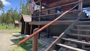 A rustic wooden cabin with a porch and a staircase leading to an upper level. - Stratton Ranch - Wyoming Getaway Cabin - 4 bed/2 bath WY Cabin! (Dubois)