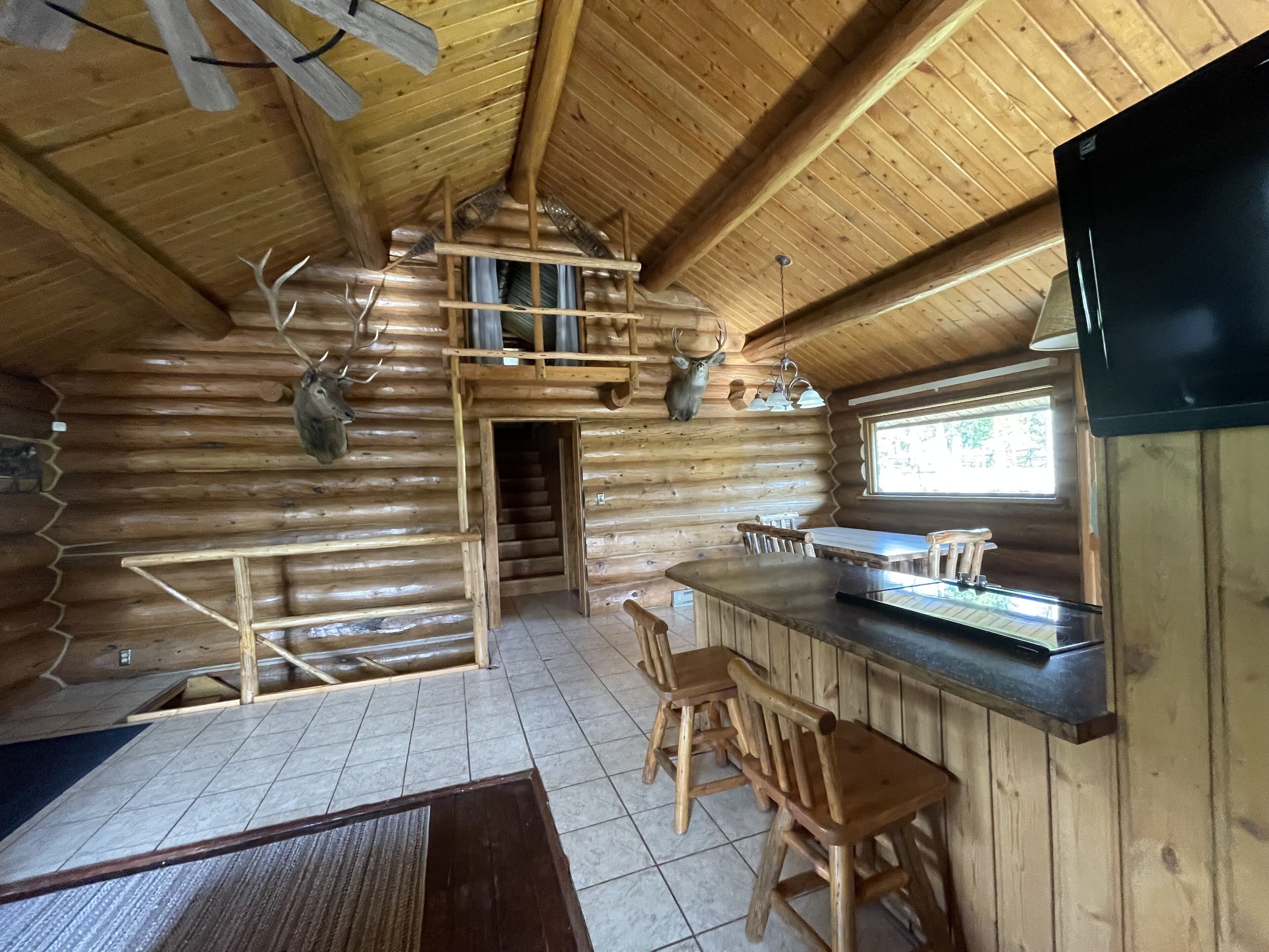 L’intérieur d’une cabane en rondins comprend un coin cuisine, une table à manger en bois et des chaises.