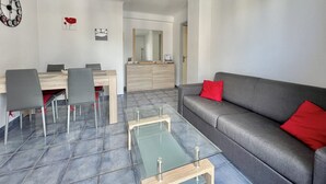 A modern living room with a grey sofa, a glass coffee table, and a dining area with a wooden table and chairs. - Luminous cocoon near the beach (Saint-Raphaël)
