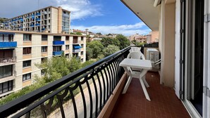 A balcony with a table and chairs, overlooking a residential area with multi-story buildings and a clear sky. - Luminous cocoon near the beach (Saint-Raphaël)