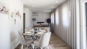 Un comedor moderno con una mesa de vidrio, sillas tapizadas de gris y un florero central.