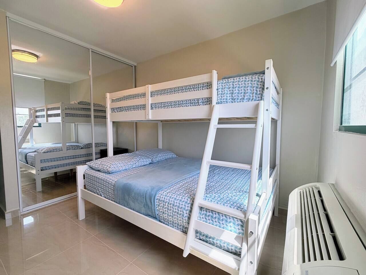 Een slaapkamer met een stapelbed, een spiegelkast en een radiator.