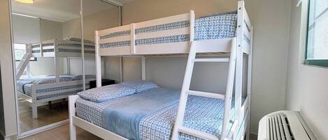 Een slaapkamer met een stapelbed, een spiegelkast en een radiator.