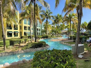 Ein Resort mit Swimmingpool, Palmen und einem Gebäude mit mehreren Balkonen.