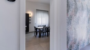 Un coin repas avec une table et des chaises, un panneau accroché au mur et une fenêtre avec des rideaux.