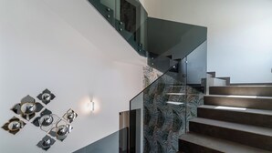 A modern staircase with glass railings and a patterned wall.
