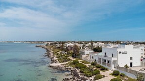 A coastal residential area with modern white buildings, a clear blue sky, and a calm sea.