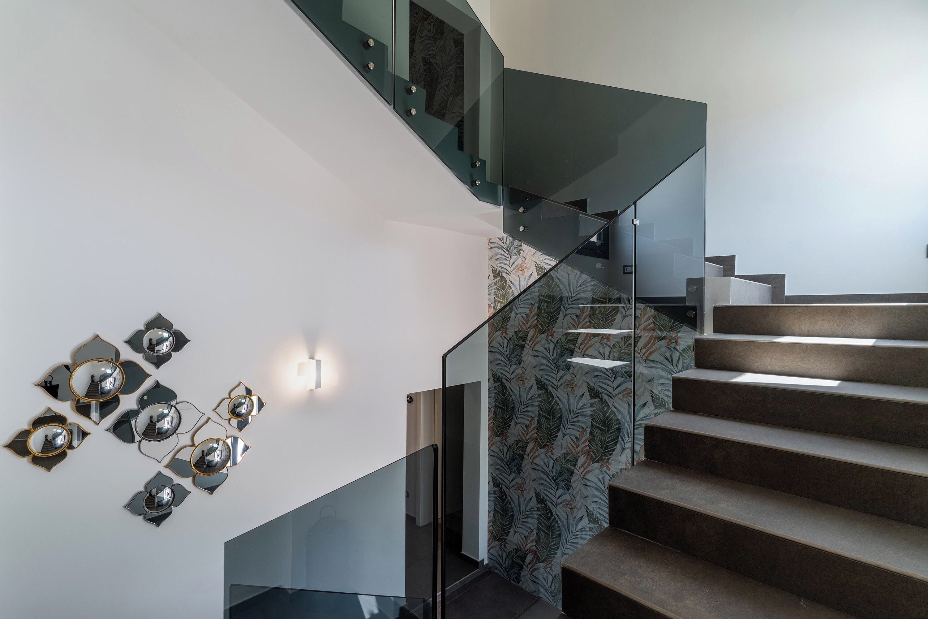 Una moderna scala con ringhiere in vetro e una parete decorata.
