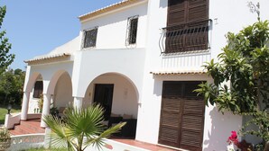 A two-story building with a white facade, multiple balconies with metal railings, and a small garden area with a palm tree. - Villa Alcaide (Portimão)
