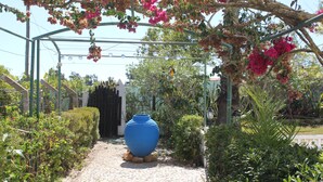 A cobblestone pathway leading to a covered area with a large blue vase and various plants. - Villa Alcaide (Portimão)