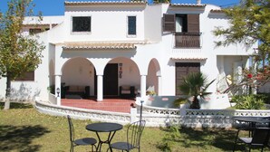 A white building with arches, a patio, and a small garden. - Villa Alcaide (Portimão)