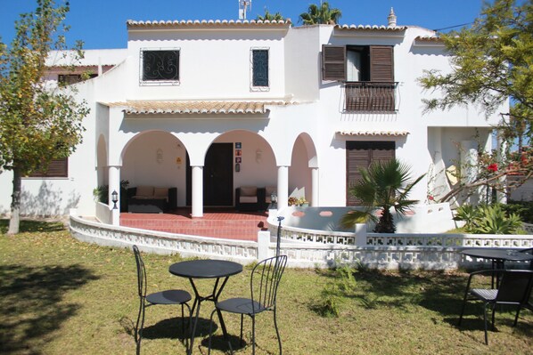 Un edificio blanco con arcos, un patio y un pequeño jardín.