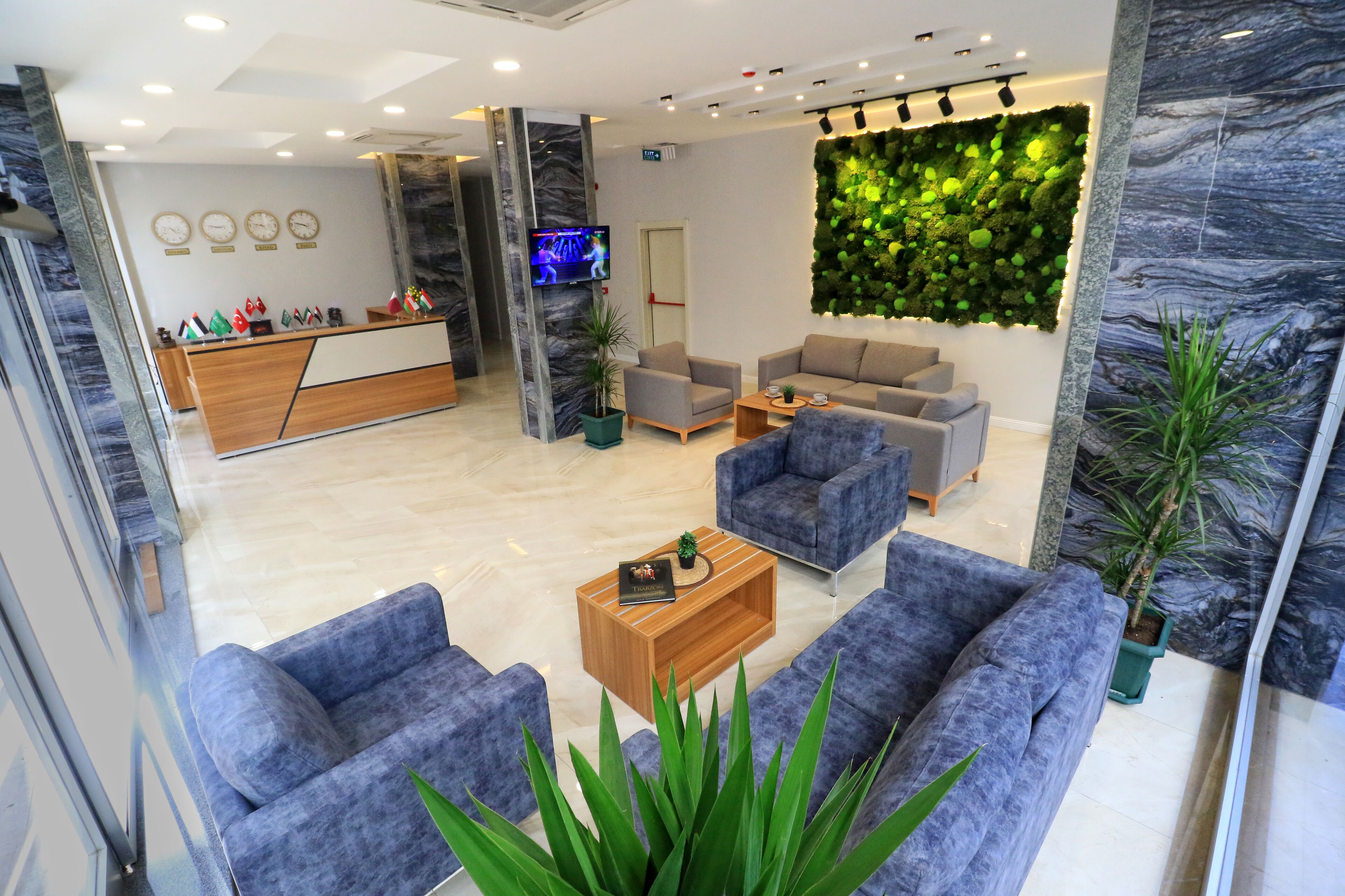 Eine moderne Lobby mit Empfangstresen, Sitzgelegenheiten und einer Wand mit Pflanzen.