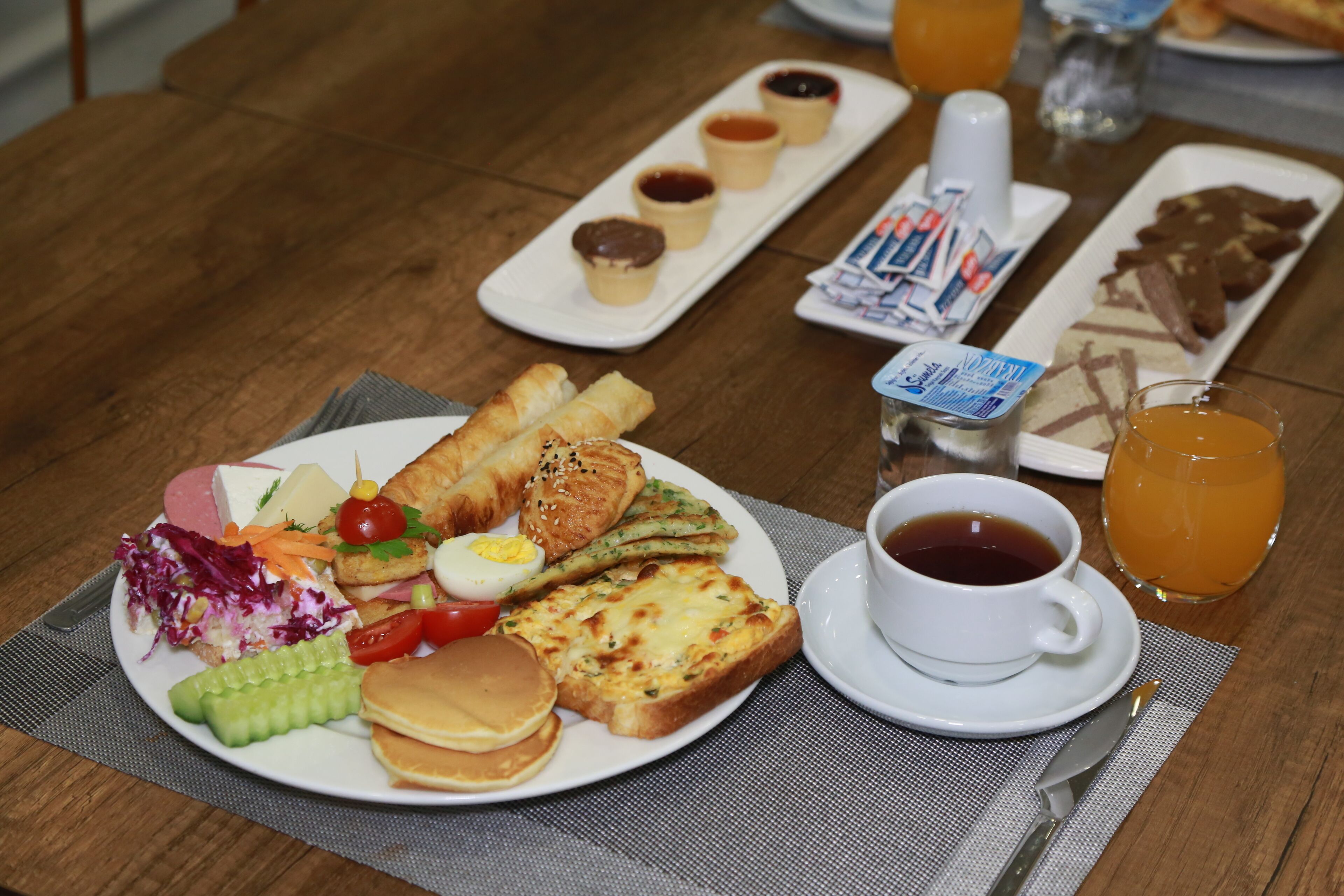 Un desayuno con tortitas, huevos, tostadas y una variedad de acompañamientos.