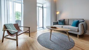 A modern living room with a sofa, a chair, a coffee table, and a floor lamp. - Nomad's Lux - Jardim à Vista (Porto)