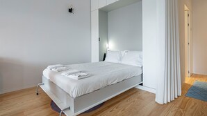 A minimalist bedroom with a bed, a nightstand, and a curtain. - Nomad's Lux - Jardim à Vista (Porto)