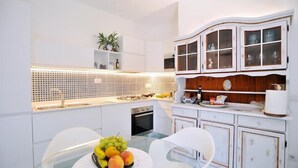 A modern kitchen with white cabinetry, a central island, and a fruit bowl on the table.