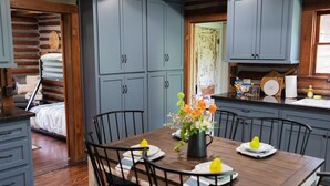 A cozy log cabin interior with a dining area featuring a wooden table, chairs, and a vase of flowers. - Rustic Charm with Modern Amenities, Two Creeks Crossing Resort (Livingston)
