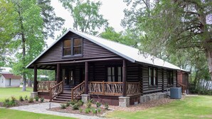A log cabin with a porch, steps, and a stone foundation. - Rustic Charm with Modern Amenities, Two Creeks Crossing Resort (Livingston)
