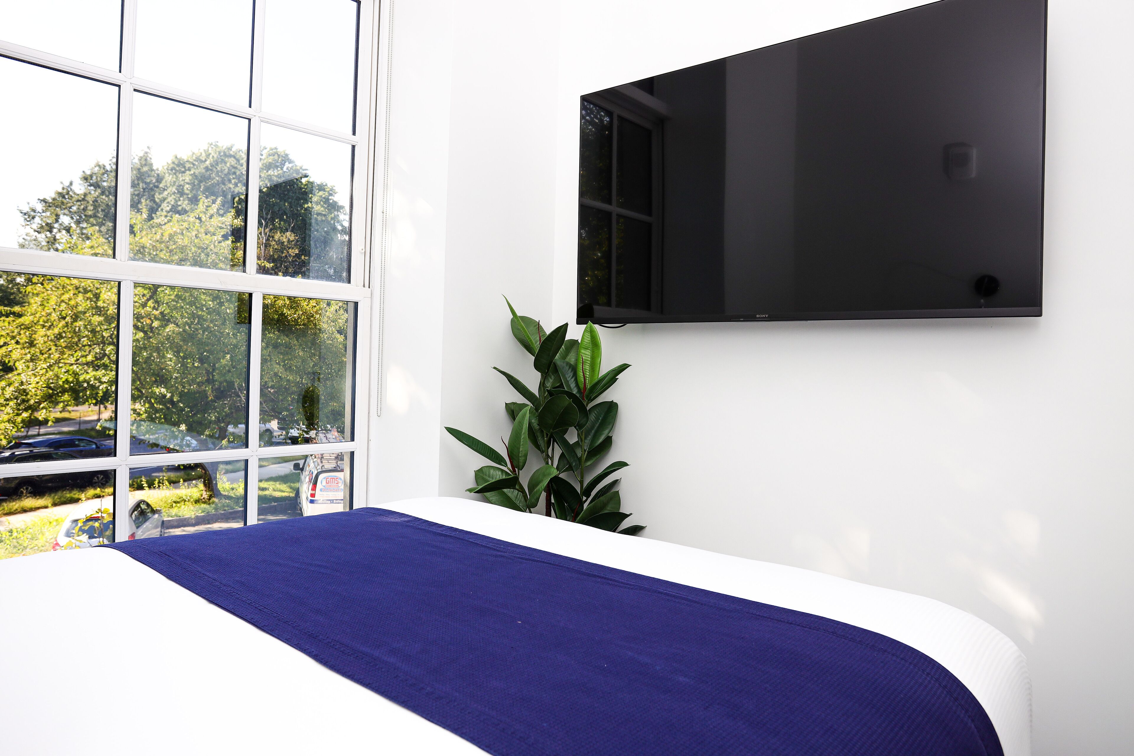 A bedroom with a bed, a window, and a wall-mounted TV.