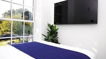 A bedroom with a bed, a window, and a wall-mounted TV.