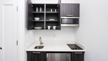 Una cocina moderna con microondas integrado, refrigerador de acero inoxidable y encimera de mármol.