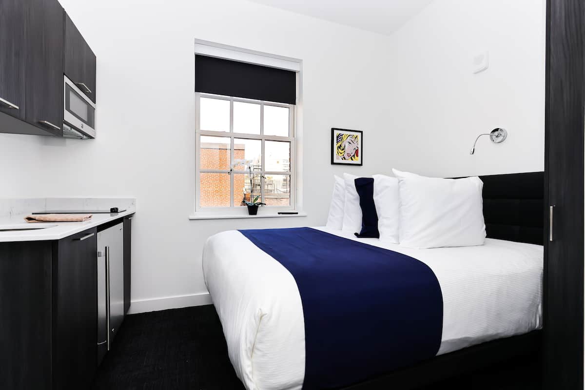 A modern bedroom with a bed, a desk, and a window.
