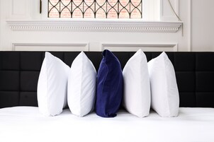 Een bed met een zwart hoofdeinde en witte beddengoed.